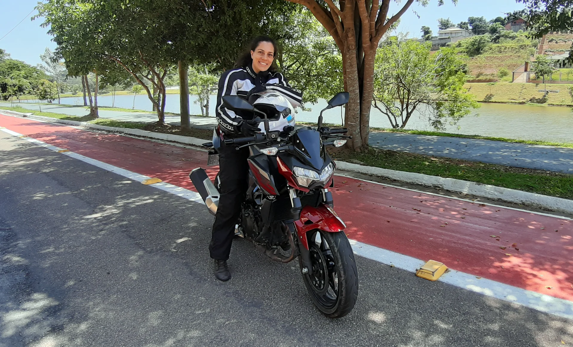 Juliana @casalcrepaldi sorrindo com capacete na mao ao lado de uma moto