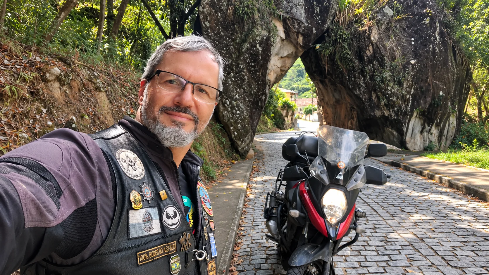 Baraldo, criador do Caminhos de Motos, ao lado da moto em estrada serrana do RJ